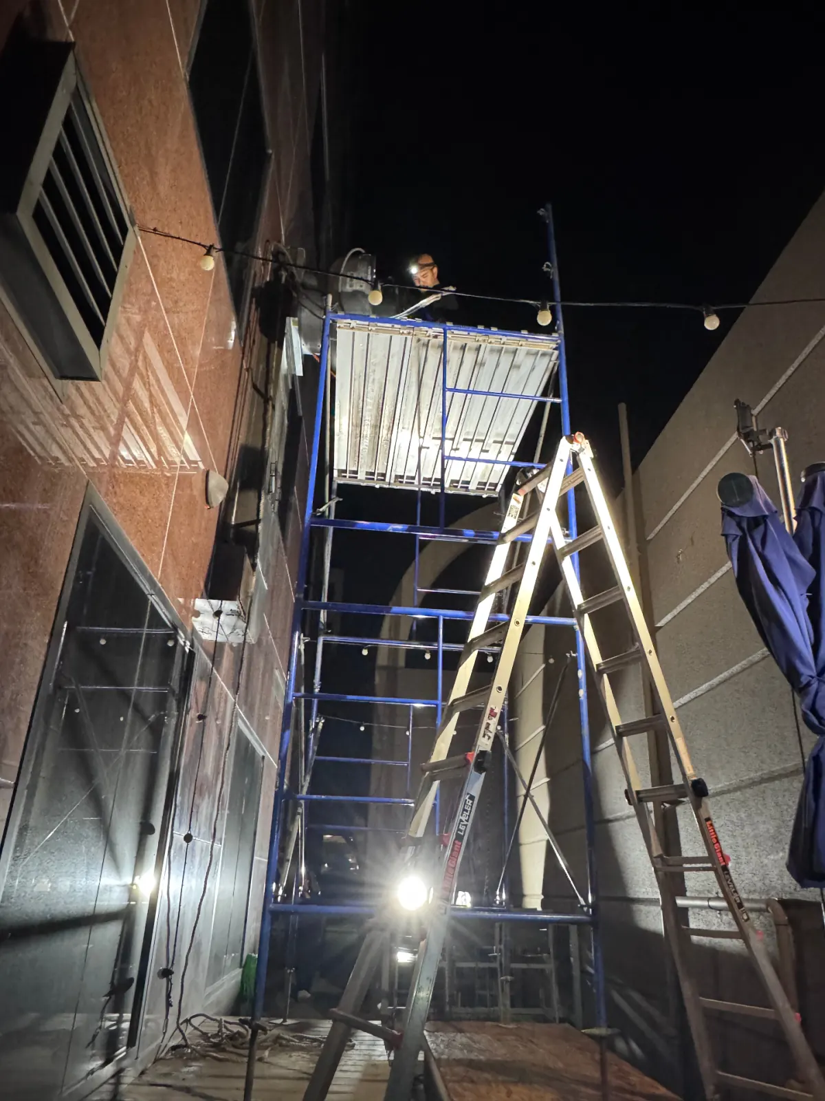 Wide view of scaffold setup for nighttime exterior fan service