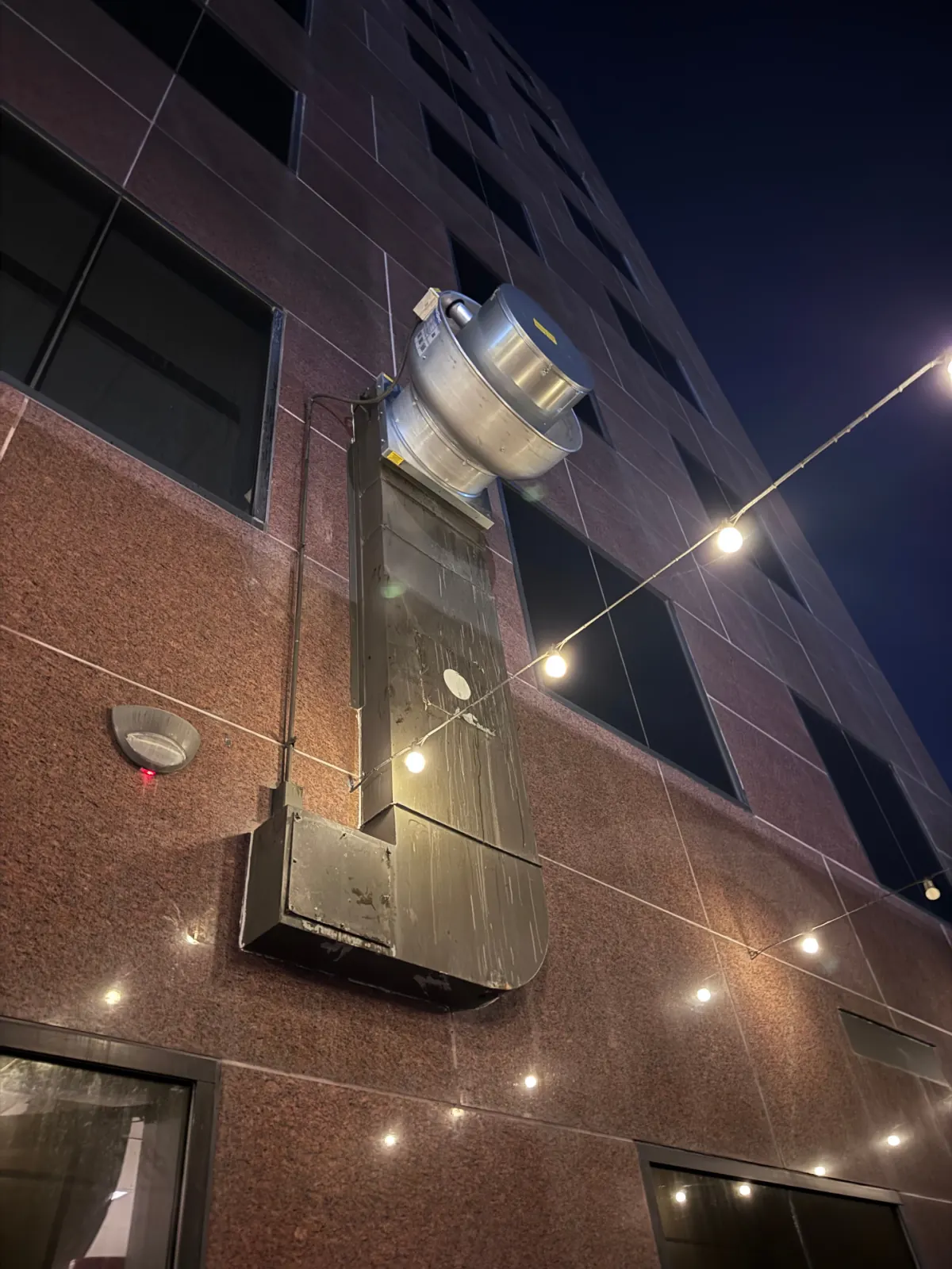 Upblast exhaust fan and exterior duct mounted on building facade