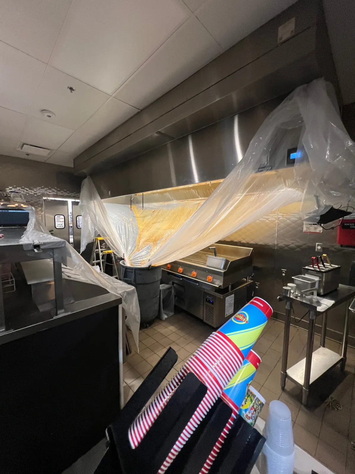 Kitchen hood and cook line protected with plastic sheeting during cleaning