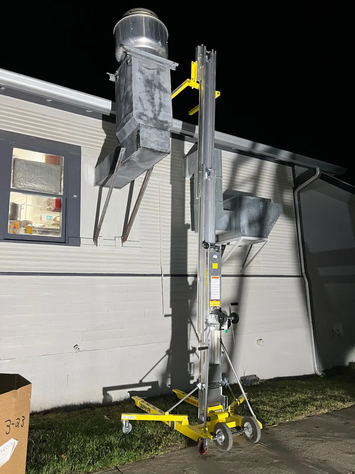 Material lift staged beside exterior duct and upblast fan for removal