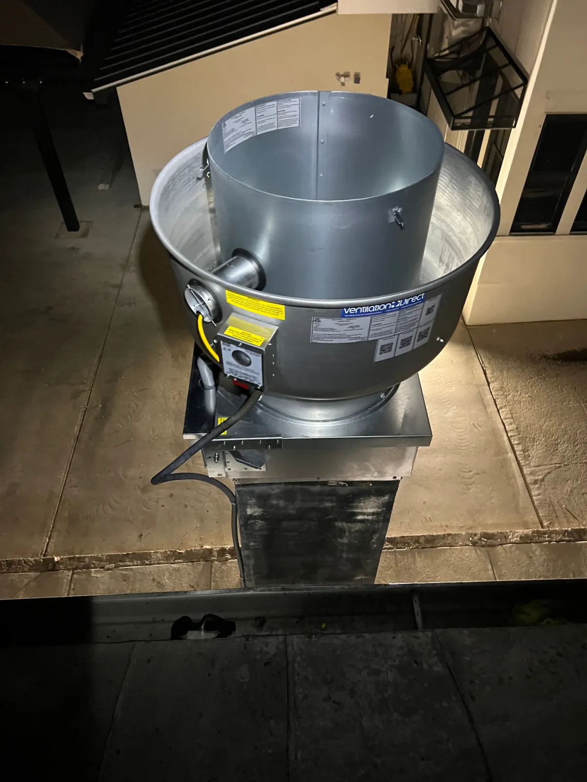 New ventilation upblast exhaust fan staged on rooftop curb before install