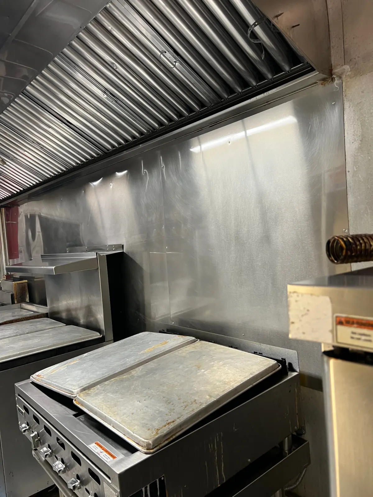Cleaned hood baffles and stainless backsplash above commercial range