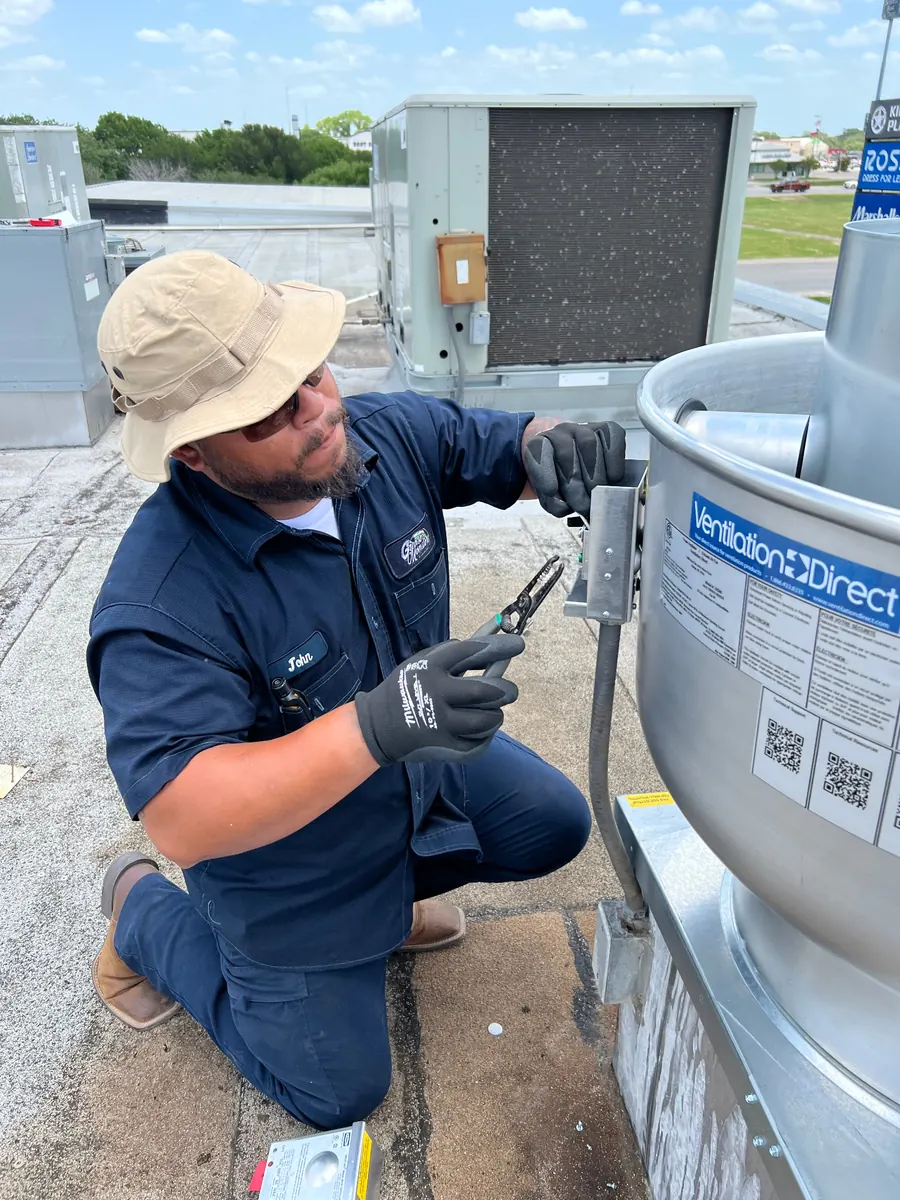 Technician servicing rooftop exhaust fan motor