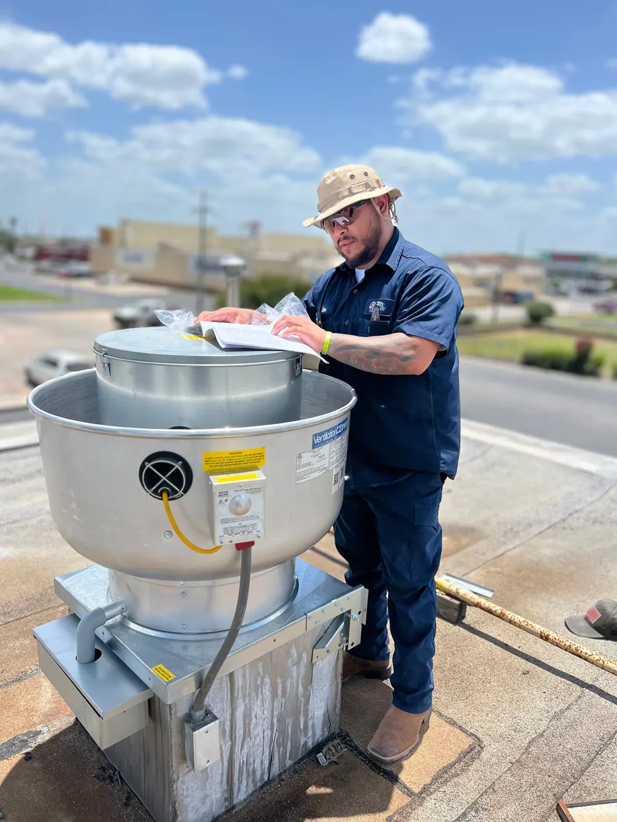 Technician inspecting upblast fan documentation